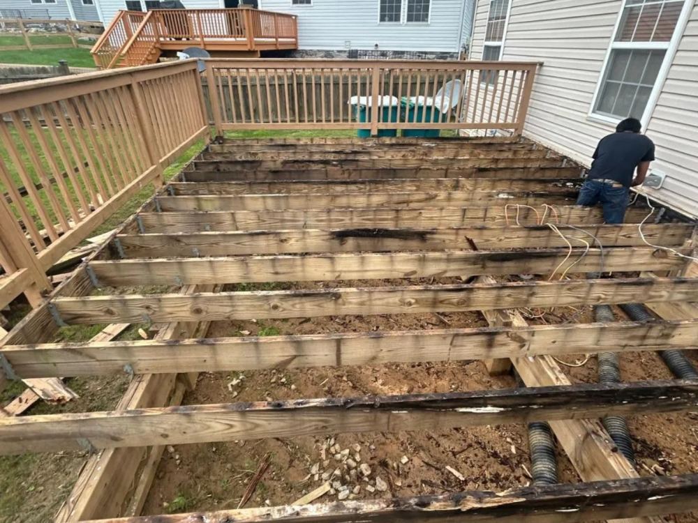 Deck stripped to joists revealing damaged framing prior to repair